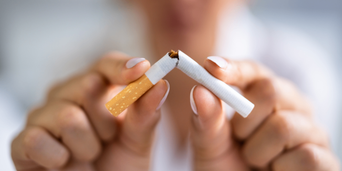 Mãos quebrando cigarro ao meio como símbolo de prevenção ao câncer de pulmão